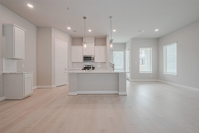 8915 Grovner Pl, Houston, TX 77055 - kitchen featuring stainless steel microwave, tasteful backsplash, baseboards, white cabinets, and light wood-style floors