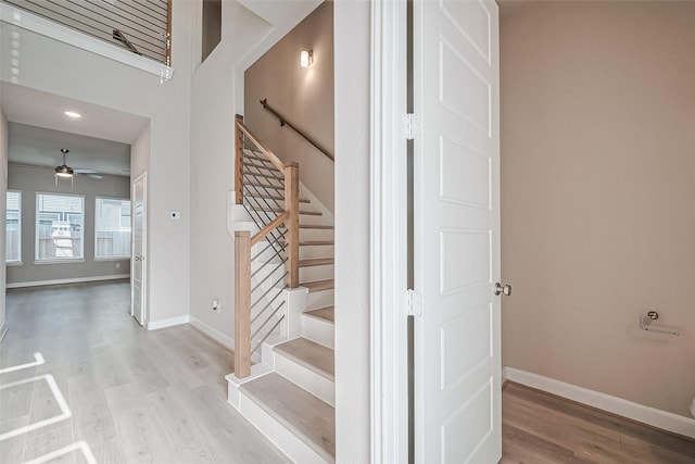stairway featuring wood finished floors, ceiling fan, and baseboards