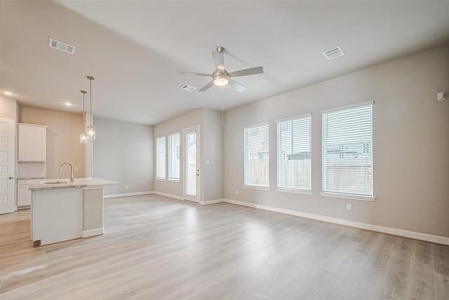 unfurnished living room featuring light wood-style floors, visible vents, baseboards, and ceiling fan