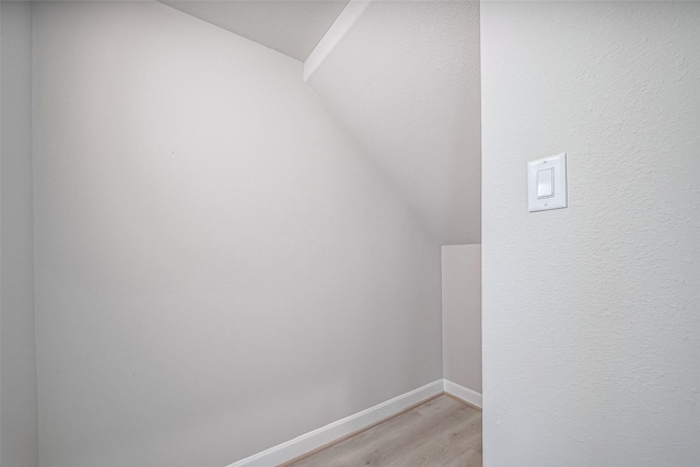 additional living space with light wood-style flooring, baseboards, and lofted ceiling