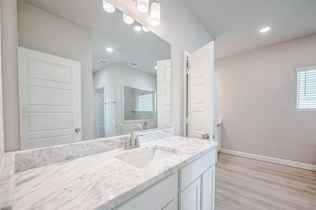 bathroom with a shower with shower door, vanity, visible vents, wood finished floors, and baseboards