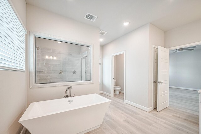 bathroom with visible vents, a tile shower, toilet, a ceiling fan, and wood finished floors