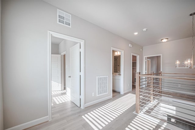 unfurnished bedroom with a chandelier, baseboards, visible vents, and light wood-style flooring