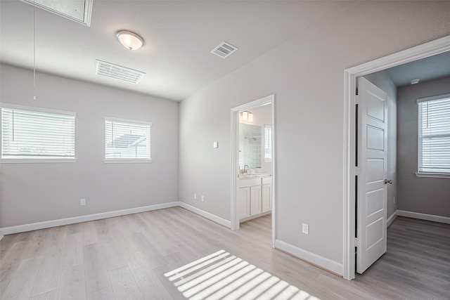 unfurnished bedroom featuring light wood-style floors, visible vents, baseboards, and attic access