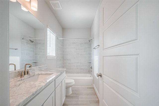 bathroom featuring vanity, visible vents, toilet, shower / bath combination, and wood finished floors