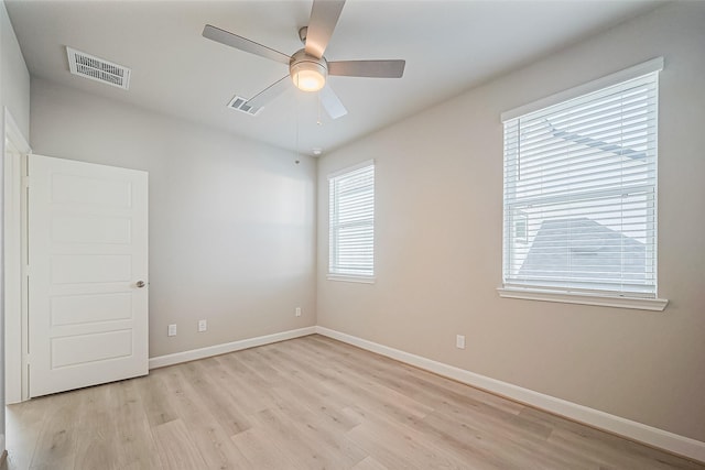 spare room featuring light wood-style floors, ceiling fan, baseboards, and visible vents