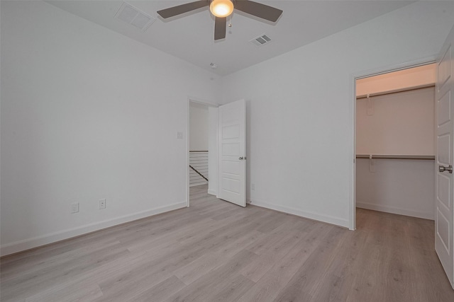 1611 Regents Gate Ct, Houston, TX 77055 - unfurnished bedroom with light wood-style flooring, a walk in closet, a closet, ceiling fan, and baseboards