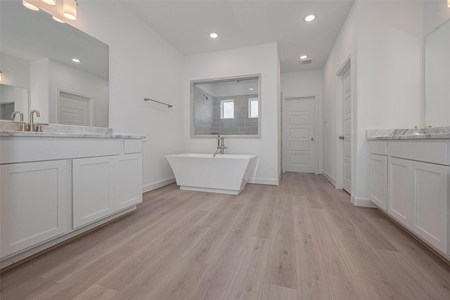 1611 Regents Gate Ct, Houston, TX 77055 - full bathroom with wood finished floors, a freestanding tub, two vanities, recessed lighting, and baseboards