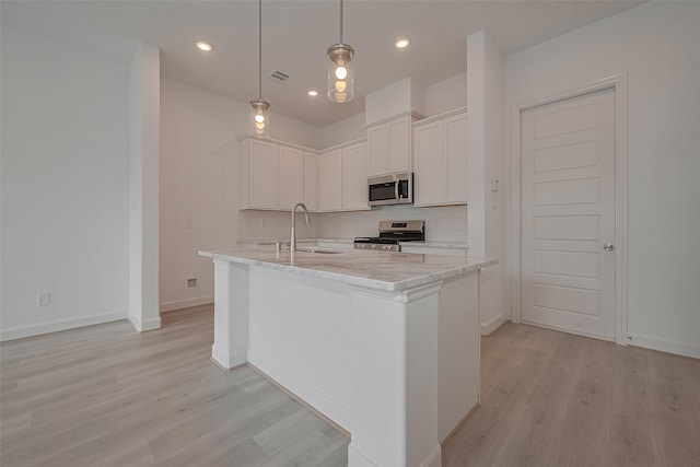 1611 Regents Gate Ct, Houston, TX 77055 - kitchen with stainless steel appliances, a sink, light wood-style floors, white cabinets, and a kitchen island with sink