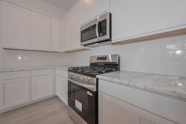 1611 Regents Gate Ct, Houston, TX 77055 - kitchen featuring stainless steel appliances, decorative backsplash, white cabinetry, and light stone countertops