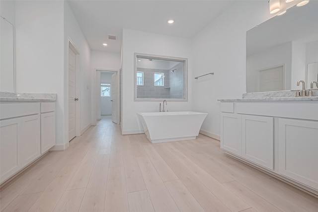 8928 Covenant Pl, Houston, TX 77055 - full bathroom featuring two vanities, a soaking tub, walk in shower, wood finished floors, and recessed lighting