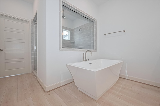 8928 Covenant Pl, Houston, TX 77055 - bathroom with a soaking tub, baseboards, and wood finished floors