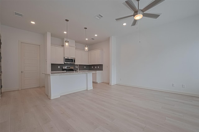8928 Covenant Pl, Houston, TX 77055 - kitchen with stainless steel appliances, light wood-type flooring, white cabinets, light countertops, and open floor plan