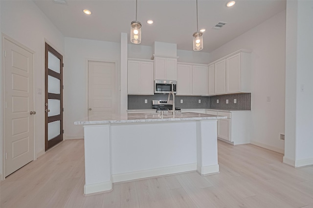 8928 Covenant Pl, Houston, TX 77055 - kitchen featuring stainless steel microwave, decorative backsplash, light wood finished floors, white cabinetry, and recessed lighting
