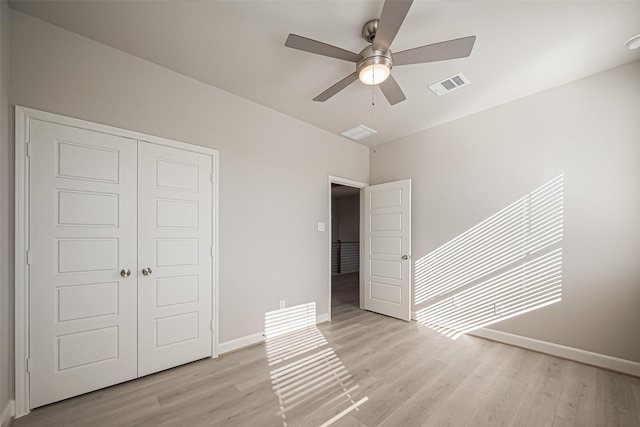 unfurnished bedroom featuring a closet, light wood finished floors, baseboards, and visible vents