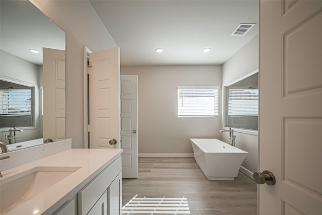 full bathroom with visible vents, baseboards, a freestanding tub, vanity, and wood finished floors