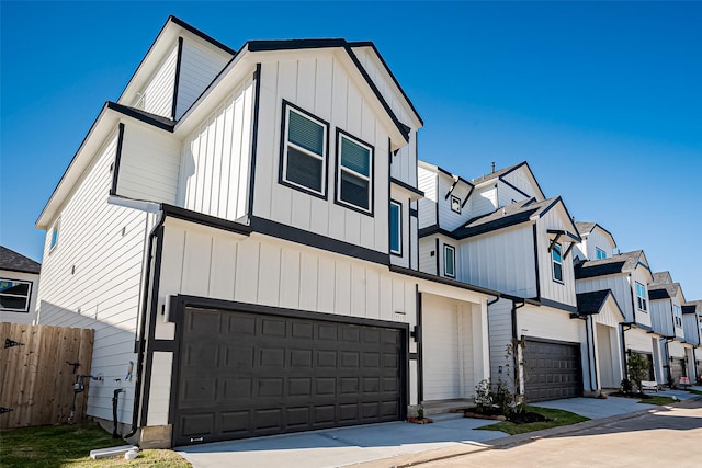 multi unit property with an attached garage, board and batten siding, fence, concrete driveway, and a residential view
