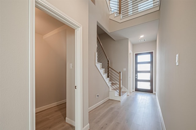 entrance foyer featuring stairs, visible vents, light wood-type flooring, and baseboards