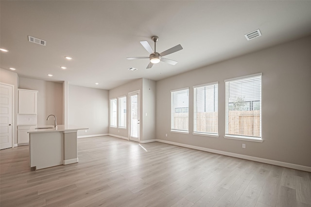 unfurnished living room with ceiling fan, a sink, visible vents, and recessed lighting