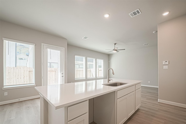 kitchen with visible vents, baseboards, a sink, and light wood-style flooring