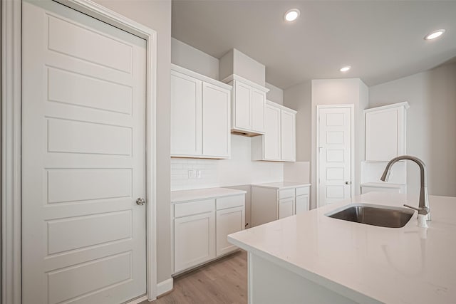 kitchen with light wood-style floors, a sink, white cabinetry, and recessed lighting