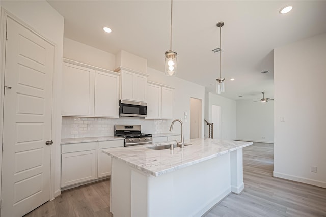 kitchen featuring tasteful backsplash, appliances with stainless steel finishes, a sink, and light wood-style floors