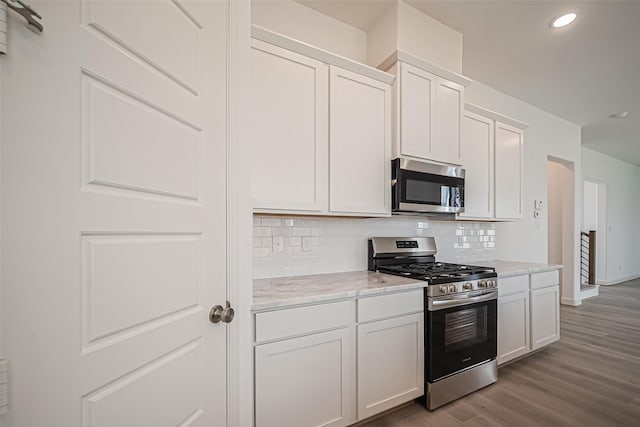 kitchen featuring recessed lighting, backsplash, white cabinets, appliances with stainless steel finishes, and wood finished floors