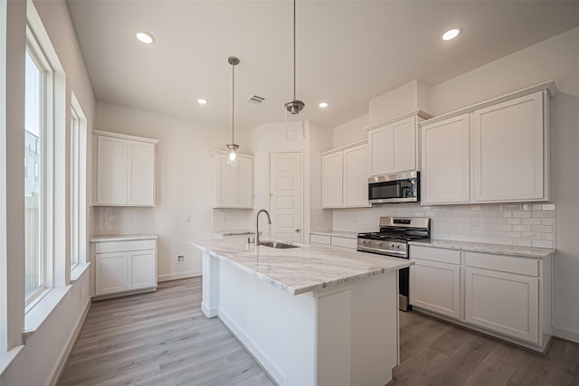 kitchen featuring appliances with stainless steel finishes, a sink, backsplash, and plenty of natural light