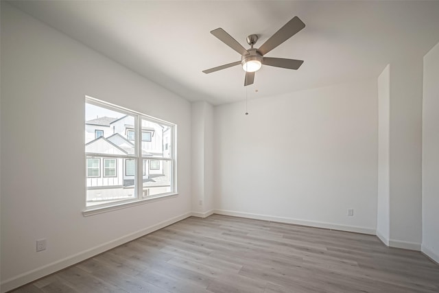 empty room with baseboards, light wood-type flooring, and a ceiling fan