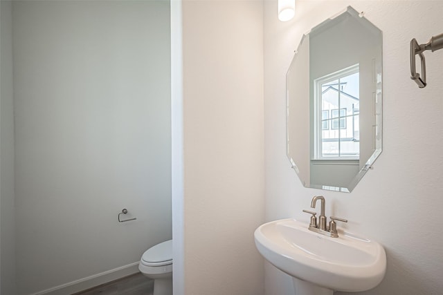 half bath featuring a sink, toilet, and wood finished floors