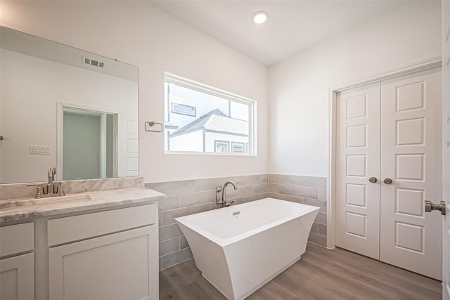 bathroom featuring visible vents, tile walls, and wood finished floors