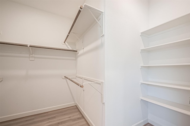 walk in closet with light wood-style floors