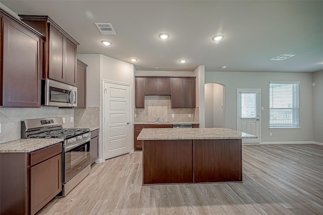 2203 Manila, Texas City, TX 77568 - kitchen with a center island, light countertops, light wood-type flooring, stainless steel appliances, and backsplash