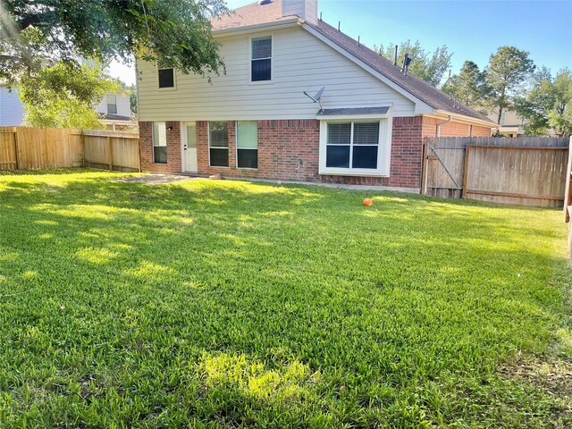 15318 Redbud Berry Way, Cypress, TX 77433 - rear view of house with a yard, a fenced backyard, a shingled roof, and brick siding