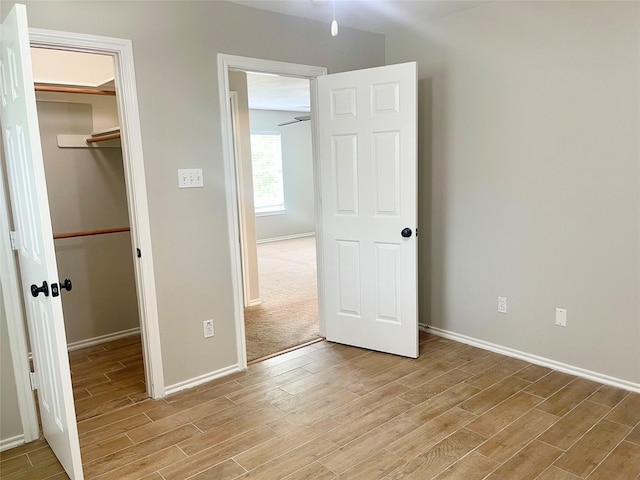 15318 Redbud Berry Way, Cypress, TX 77433 - unfurnished bedroom featuring a spacious closet, a closet, baseboards, and light wood finished floors