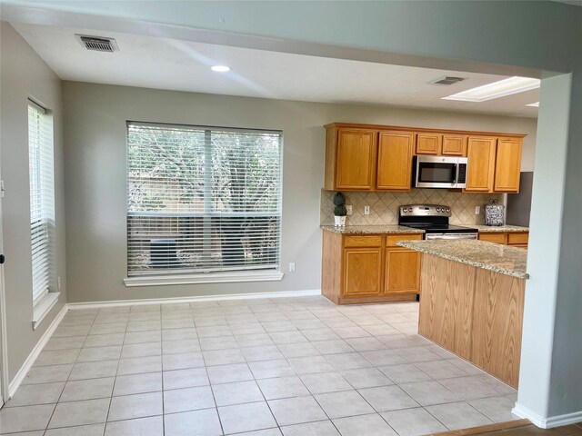 15318 Redbud Berry Way, Cypress, TX 77433 - kitchen featuring appliances with stainless steel finishes, decorative backsplash, light stone counters, and visible vents