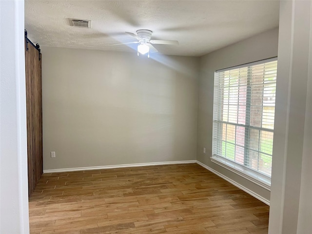 15318 Redbud Berry Way, Cypress, TX 77433 - spare room featuring light wood-style floors, a barn door, visible vents, and a wealth of natural light