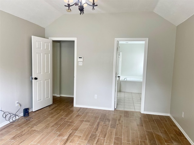 15318 Redbud Berry Way, Cypress, TX 77433 - unfurnished bedroom with a notable chandelier, baseboards, vaulted ceiling, and wood finished floors