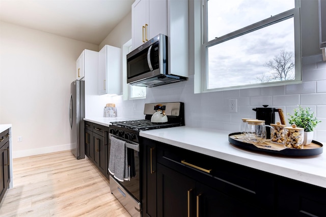 kitchen featuring backsplash, light countertops, light wood-style floors, and stainless steel appliances