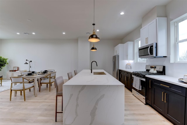 kitchen featuring light wood-style flooring, a kitchen bar, recessed lighting, appliances with stainless steel finishes, and a sink