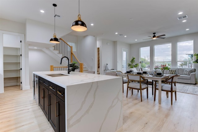 kitchen featuring visible vents, recessed lighting, a sink, open floor plan, and light wood finished floors
