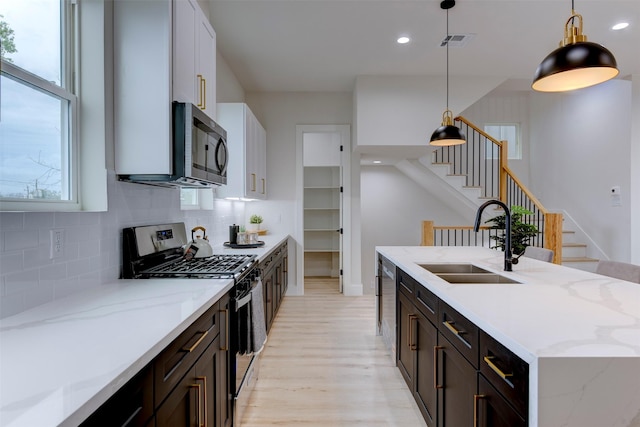 kitchen featuring light wood-type flooring, visible vents, decorative backsplash, stainless steel appliances, and a sink