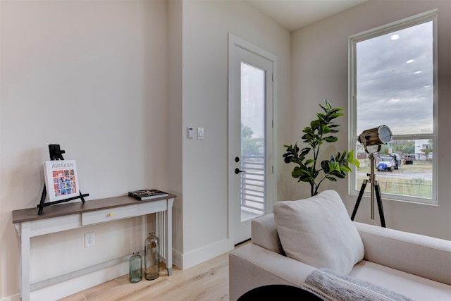 living area with light wood-type flooring and baseboards