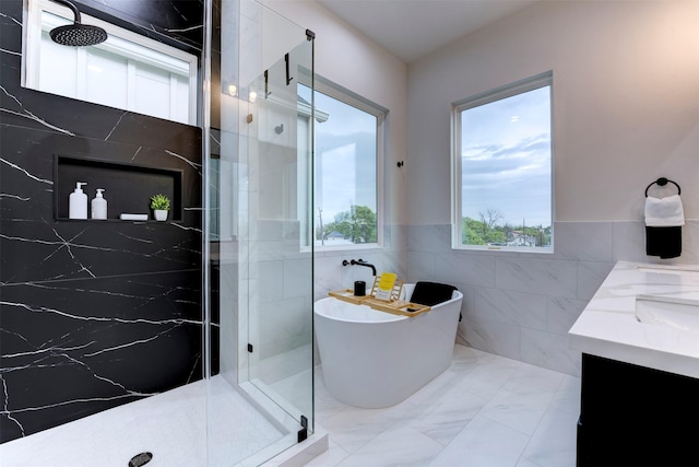 full bathroom with a freestanding bath, tile walls, double vanity, a marble finish shower, and marble finish floor