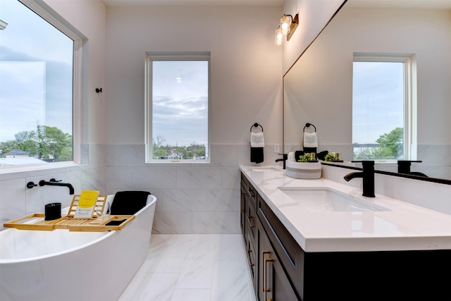 full bathroom featuring a sink, tile walls, double vanity, and plenty of natural light