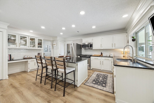 kitchen featuring stainless steel appliances, a center island, a sink, a textured ceiling, and decorative backsplash