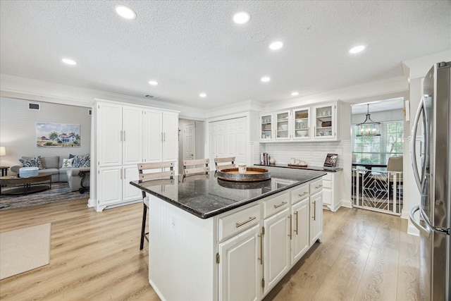 kitchen with white cabinets, freestanding refrigerator, a textured ceiling, and light wood finished floors