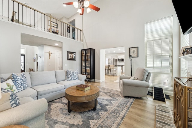 living area with wood finished floors, a towering ceiling, and ceiling fan