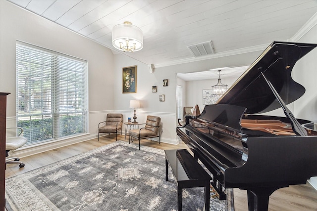 living area featuring a chandelier, wood finished floors, a wealth of natural light, and crown molding