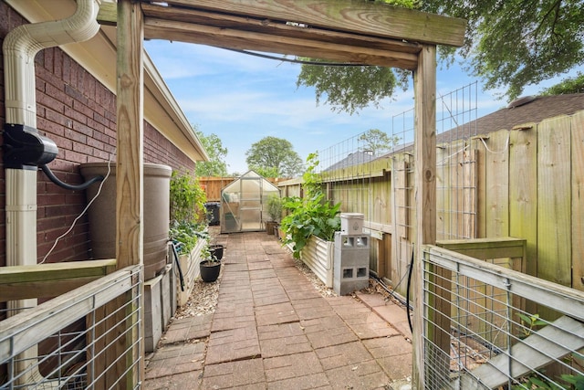 view of patio / terrace featuring an outbuilding, a fenced backyard, and a greenhouse